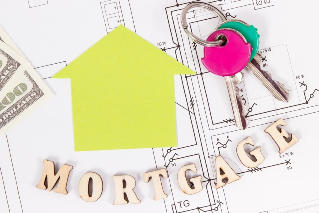 2025 year-end mortgage market recap concept image with a house-shaped arrow, house keys, cash, and blueprints symbolizing changing mortgage rates and costs for 2026 homebuyers.